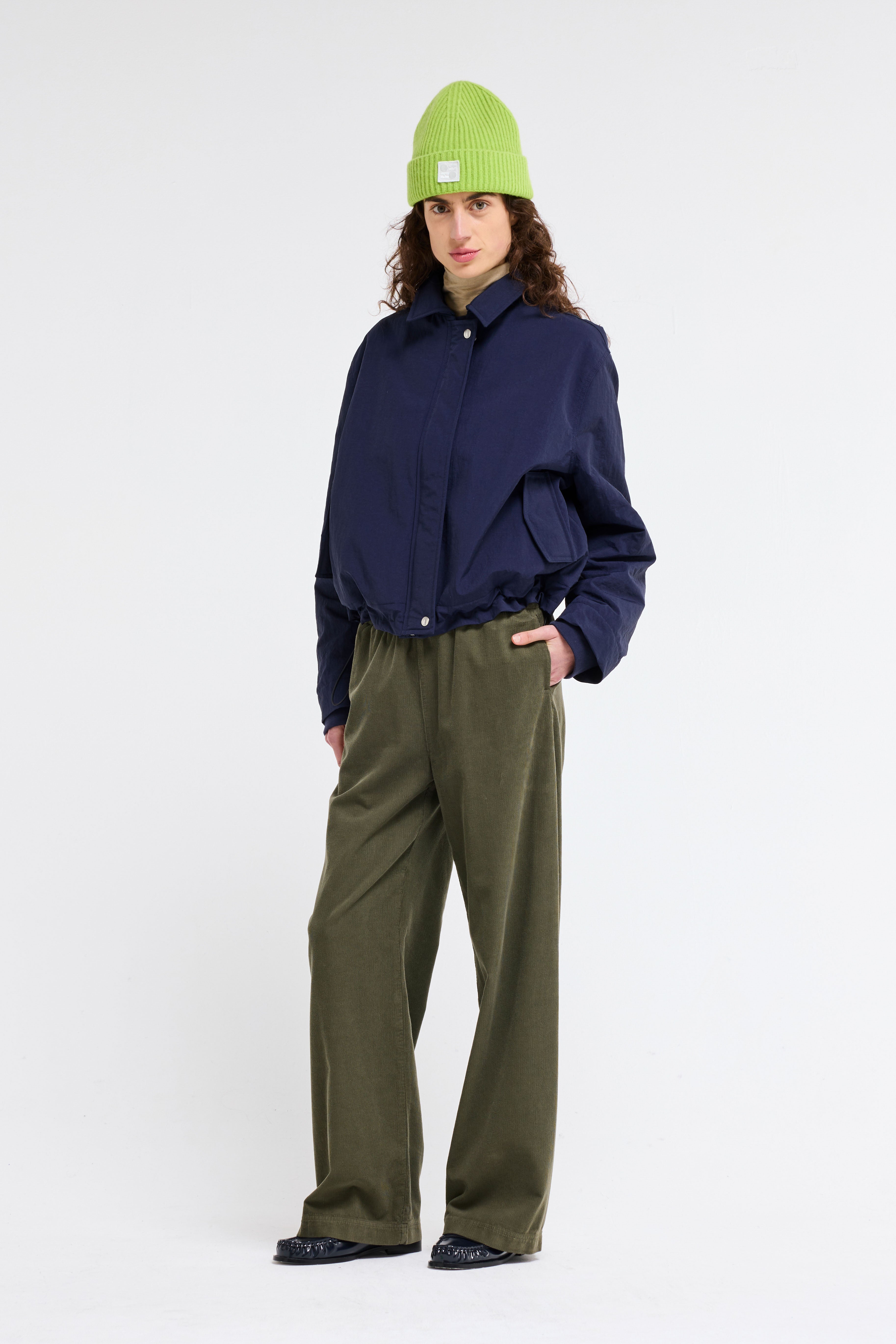 Transitional Jute Bomber Jacket in Japanese crinkle fabric, relaxed fit with detachable collar, adjustable waist, and hidden snaps for versatile layering.